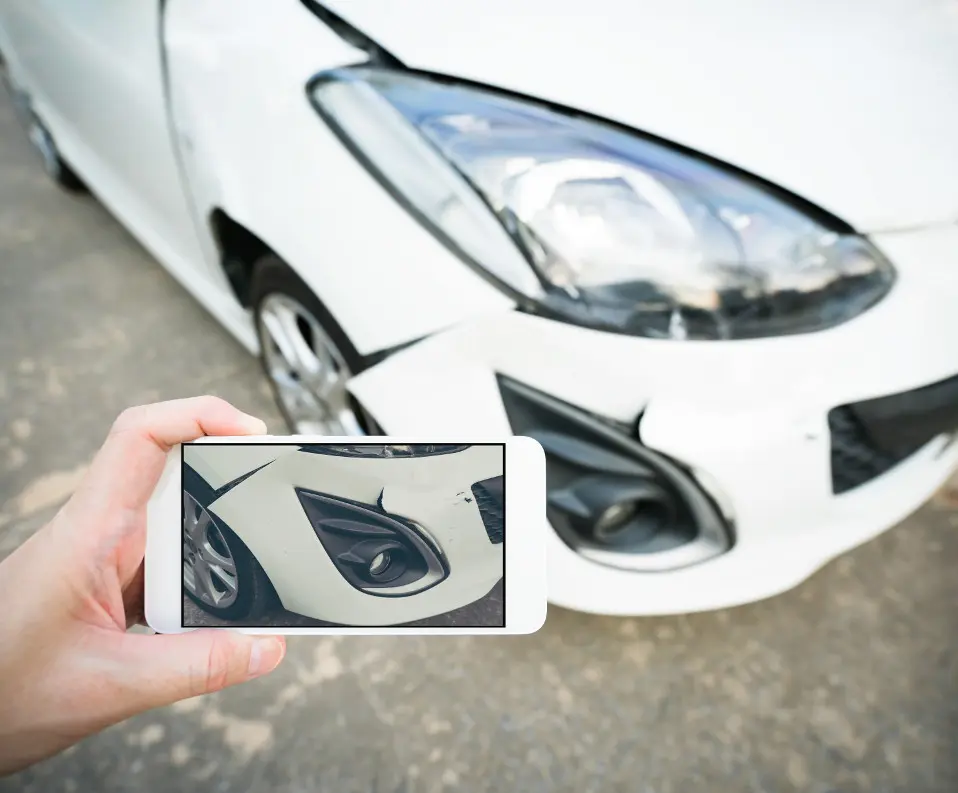 person taking a picture of car damage with cell phone